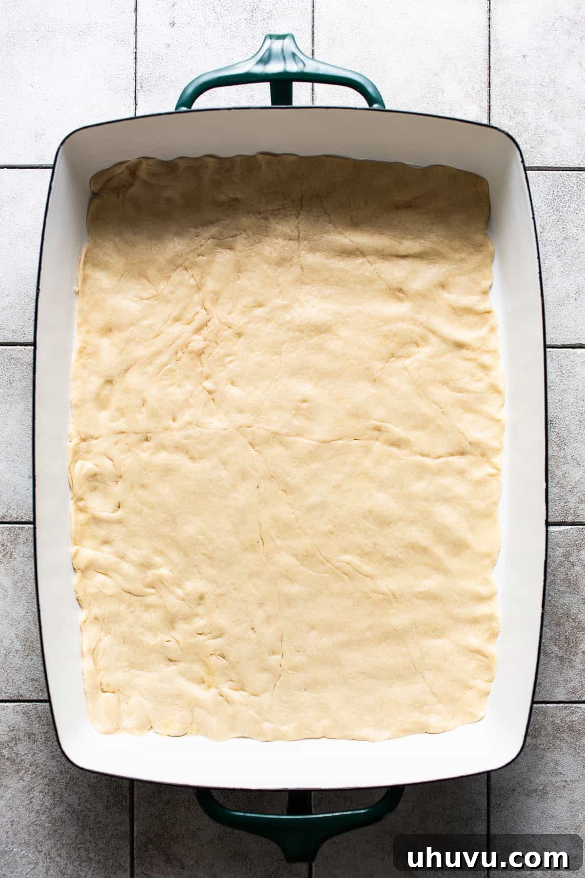 Golden Crescent Morning Bake 4 Crescent roll dough neatly pressed into a single sheet covering the bottom of a large 9x13 inch baking dish, forming the base for the breakfast casserole.