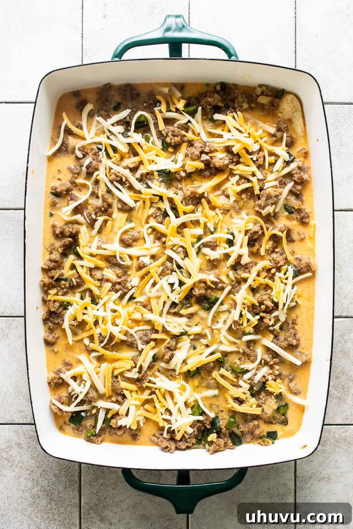 Golden Crescent Morning Bake 5 A baking dish layered with pre-baked crescent roll dough, cooked breakfast sausage, sautéed peppers and onions, and a whisked egg and cheese mixture, ready for the final layer of cheese before baking.