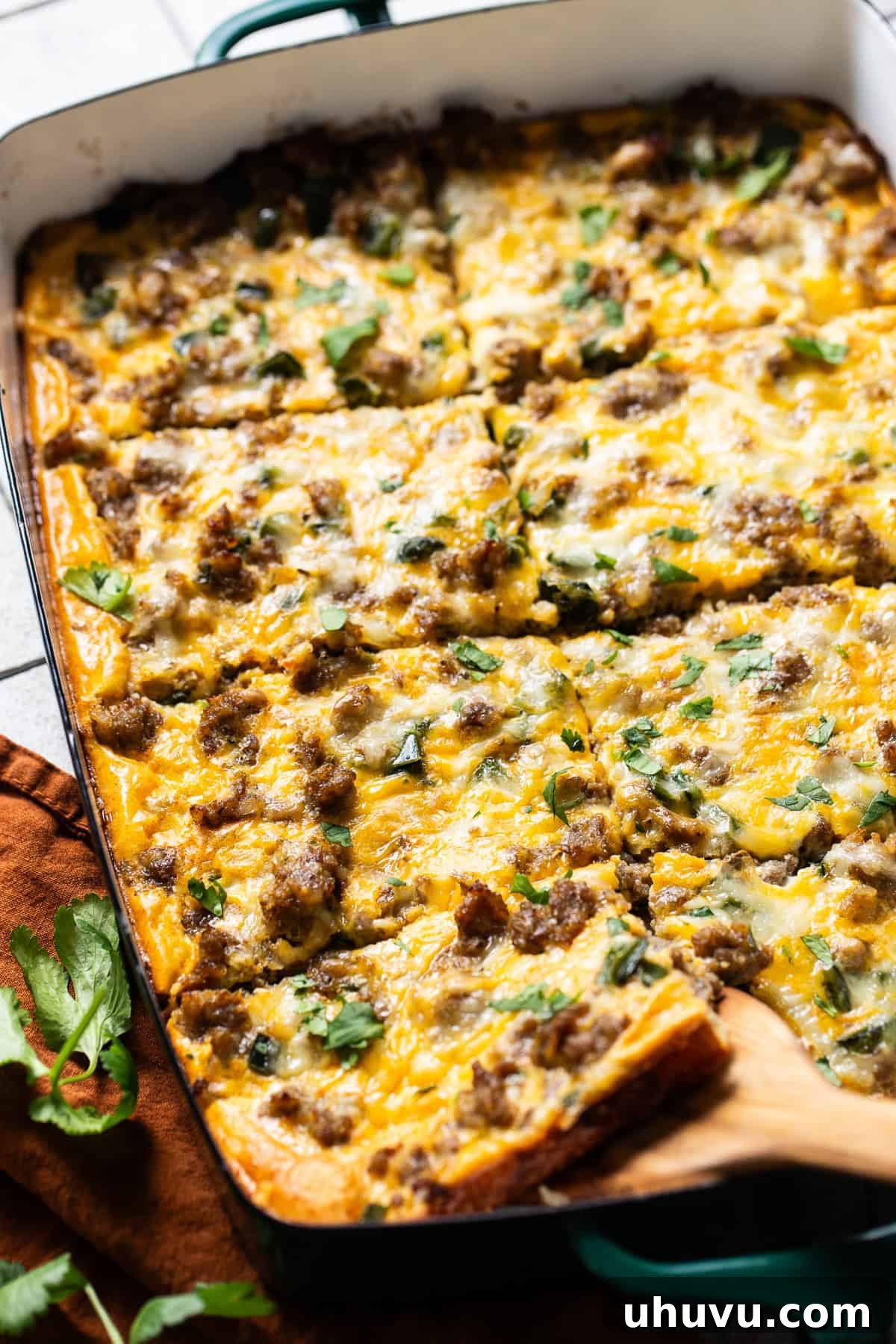 Golden Crescent Morning Bake 6 A golden brown slice of Tex-Mex Crescent Roll Breakfast Casserole being lifted from the baking dish with a wooden spatula, showing its flaky crust and savory filling.