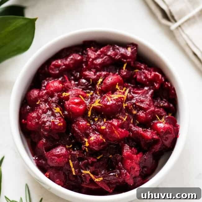 Homemade Cranberry Sauce in a white bowl, garnished with fresh orange zest.