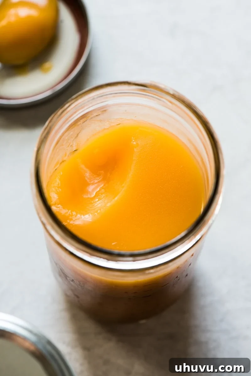 Perfect Turkey Gravy from Pan Drippings 4 A close-up of solidified fat from turkey drippings collected in a glass jar, showing its opaque texture and color.
