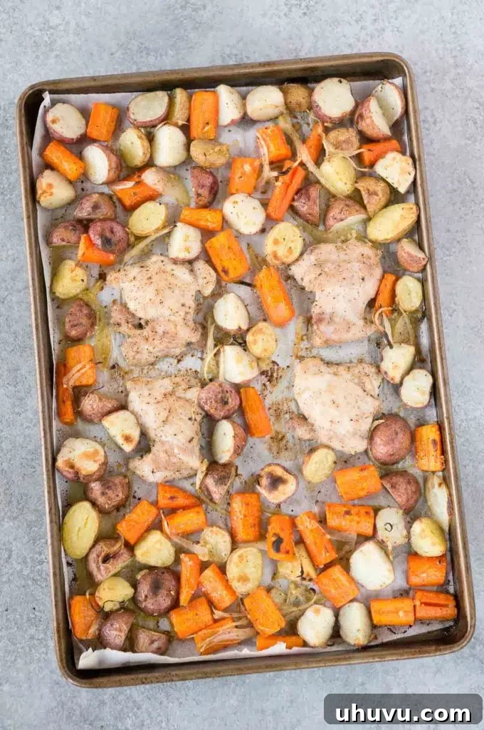 Baked chicken and potatoes on a sheet pan, garnished with fresh parsley.