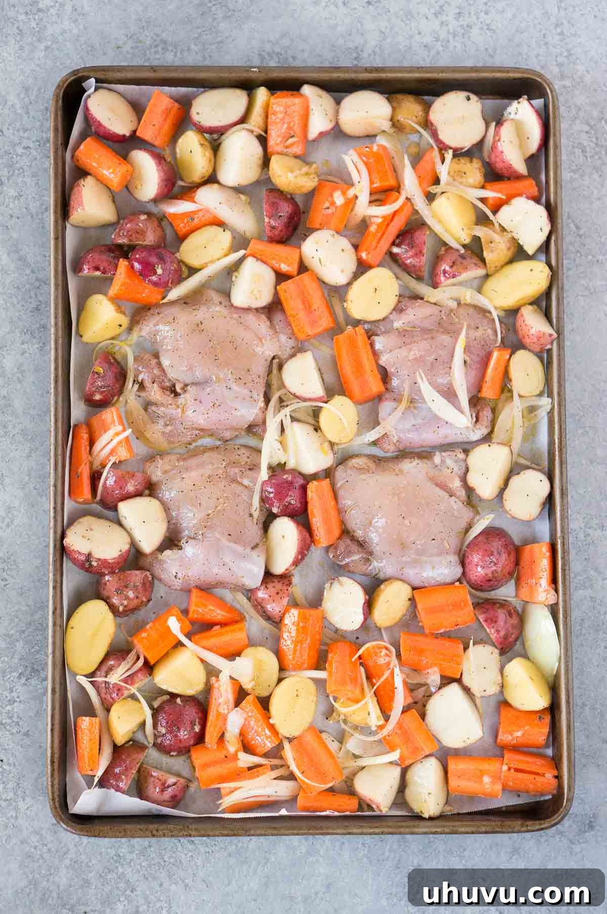 Golden Roasted Chicken and Crispy Potatoes 4 Chicken, potatoes, and carrots being seasoned in a bowl.
