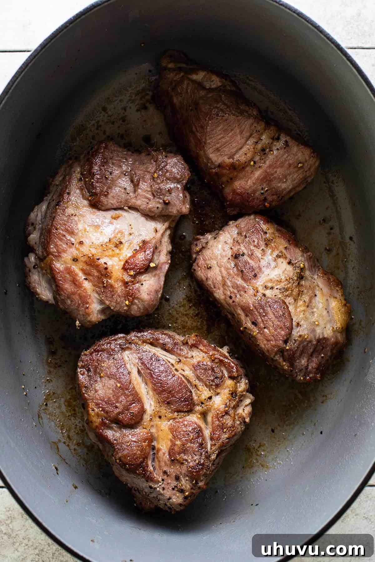 Large chunks of pork shoulder, beautifully seared and browned on all sides, resting in a large Dutch oven or pot, ready for the next step in making pozole.