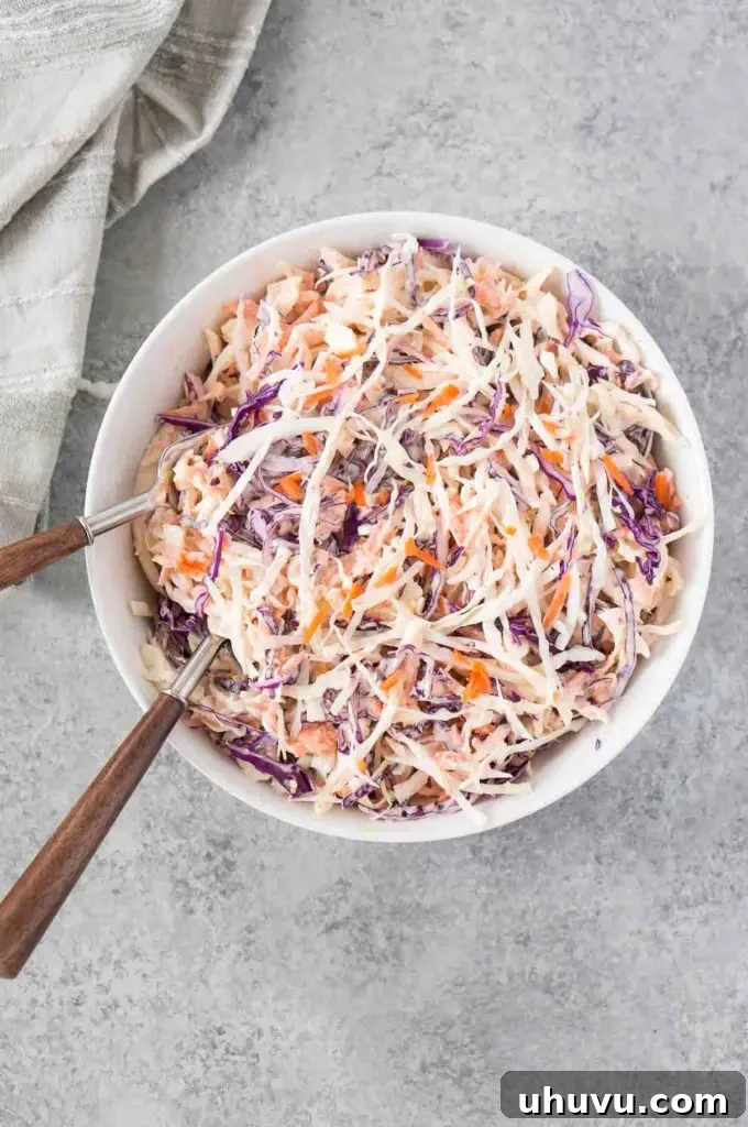 A serving of classic creamy coleslaw in a small white bowl, garnished