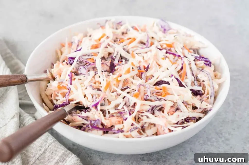 Creamy coleslaw recipe served in a large bowl with a wooden spoon for easy scooping