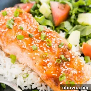 Close up of a perfectly glazed Honey Sriracha Salmon fillet served over rice.