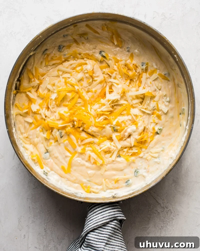 Quick Creamy Queso 5 A saute pan with shredded cheese and cream cheese melting together, showing the creamy texture starting to form.