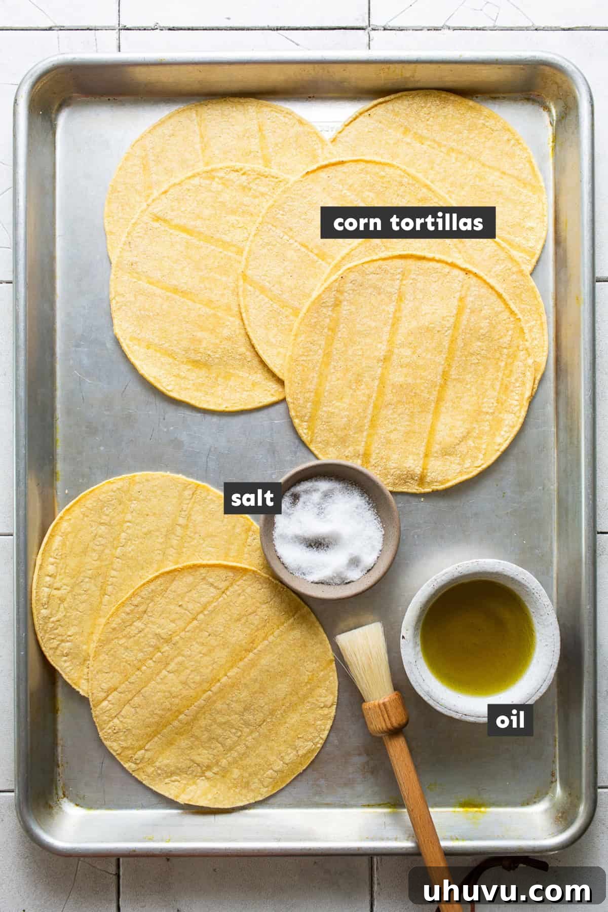 Golden Tostada Crisps 3 Ingredients for tostada shells laid out on a baking sheet, including corn tortillas, oil, and salt, ready for preparation.