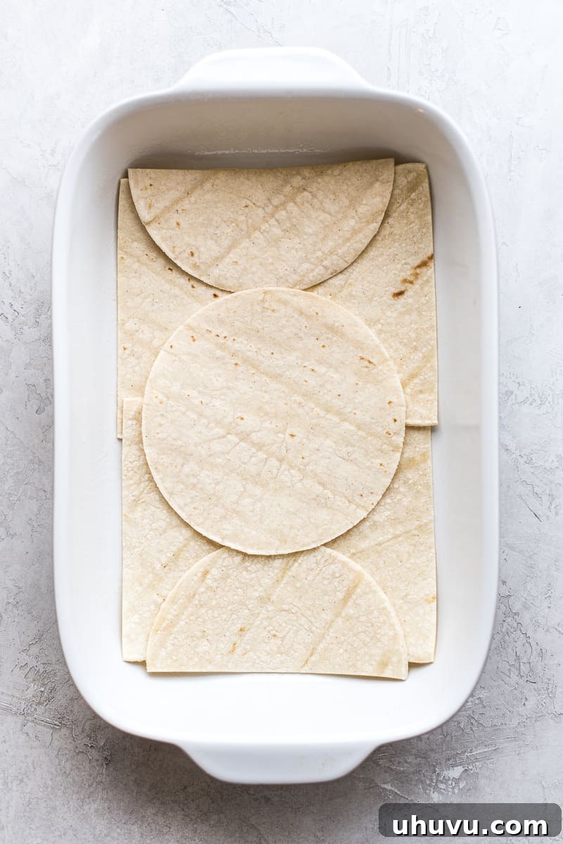 Effortless Taco Delight 7 Assembling the taco casserole with layers of tortillas, meat, and cheese.