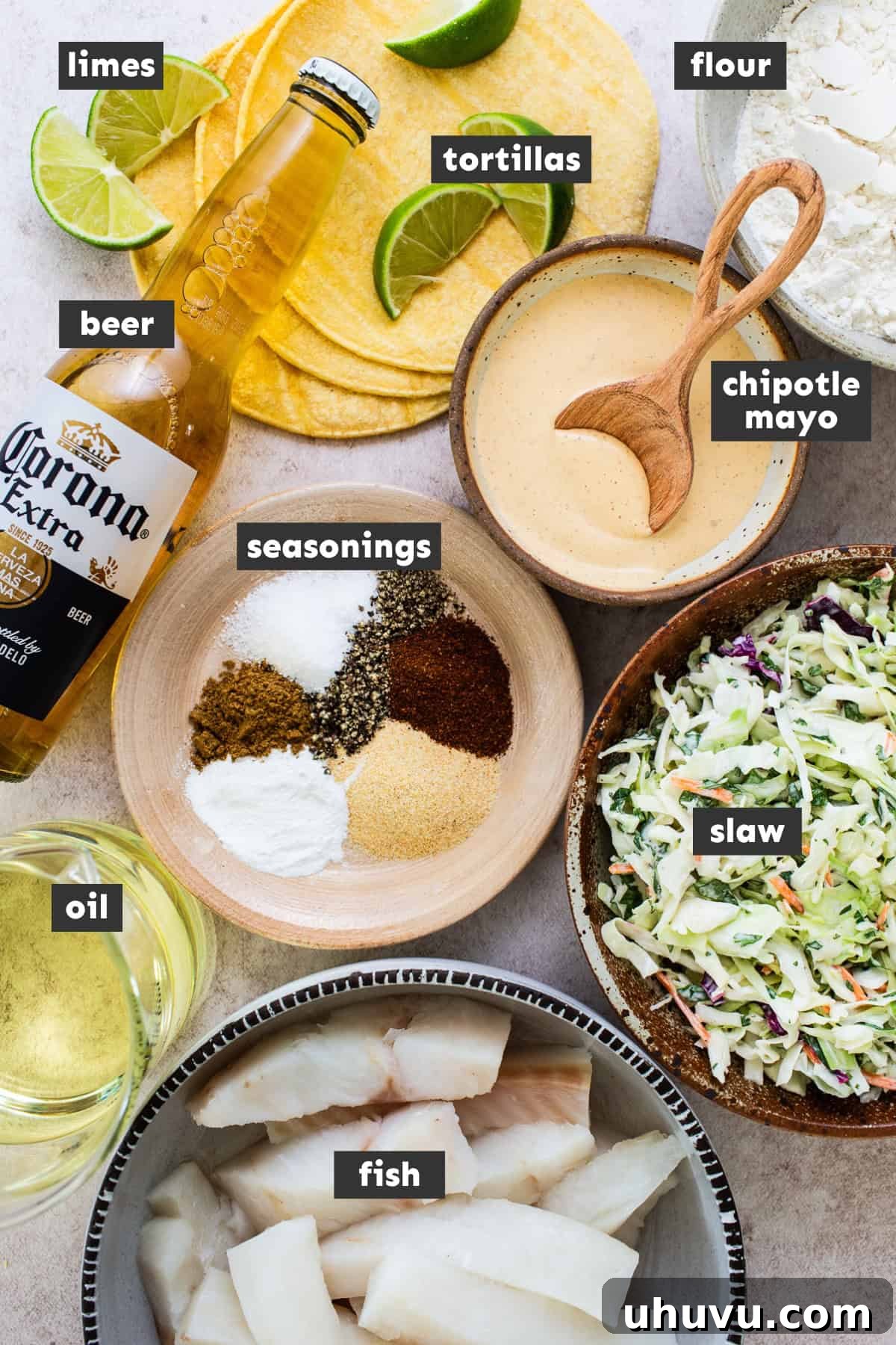 Golden Crispy Baja Fish Tacos 3 Baja fish taco ingredients laid out on a table, including fresh fish, cabbage, cilantro, limes, mayonnaise, and seasonings.