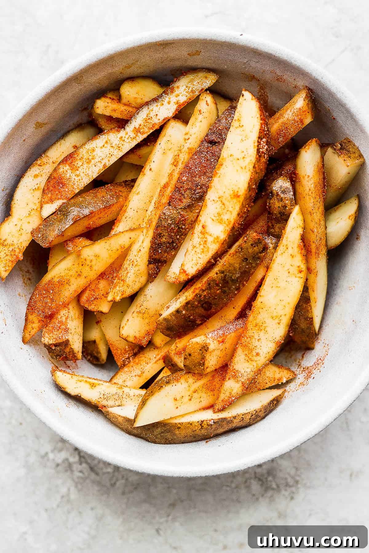 Cooked seasoned potato slices placed into a large bowl