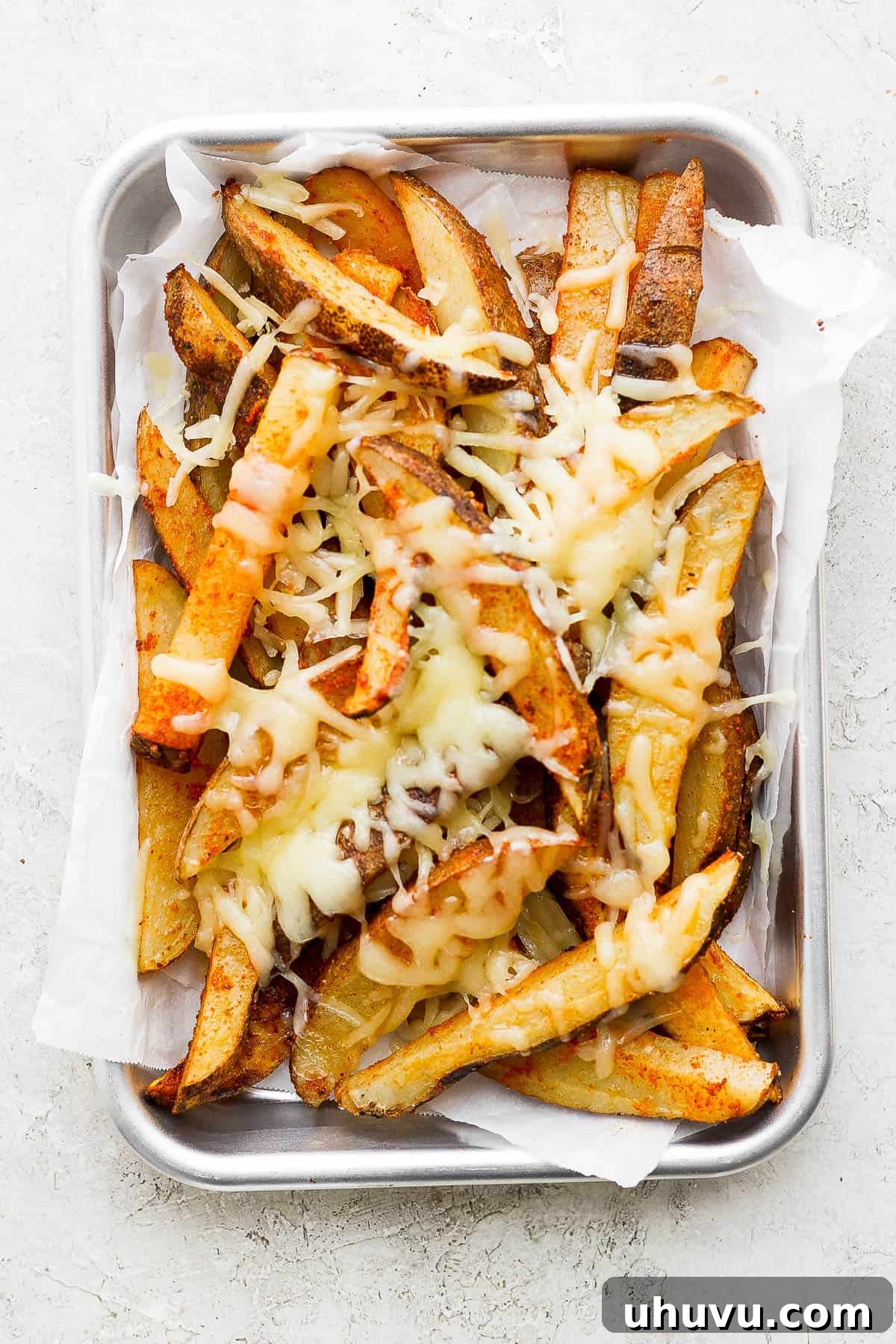 Second step in layering our carne asada fries is to top the fries with cheese. 