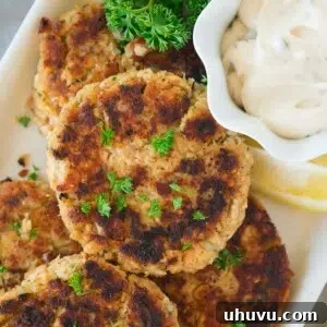 close up shot of salmon patty with tartar sauce on a platter