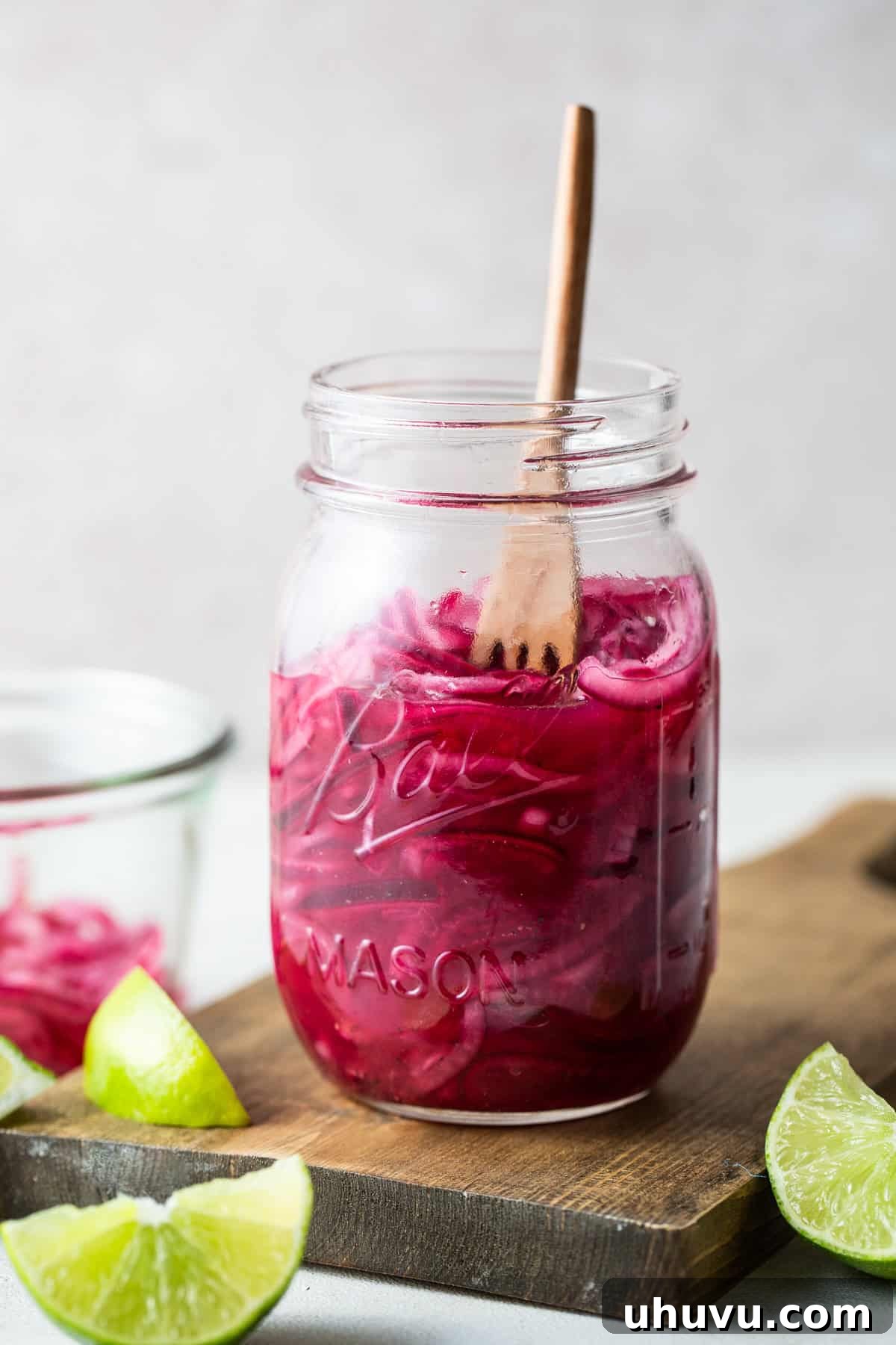 A jar of bright pink Mexican pickled red onions, perfectly cured and ready to be served, showcasing their vibrant color.