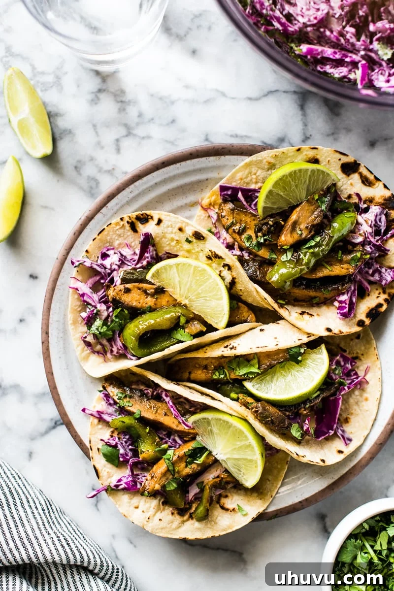 Effortless Mushroom Tacos 2 Overhead photo of vibrant, easy vegetarian mushroom tacos filled with marinated portobello mushrooms, colorful bell peppers, and a crunchy red cabbage slaw, garnished with fresh cilantro.