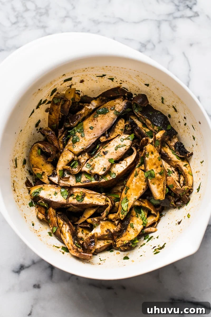 Effortless Mushroom Tacos 4 Thinly sliced portobello mushrooms tossed in a vibrant lime juice and Mexican spice marinade within a clear glass bowl, ready for cooking into vegetarian tacos.