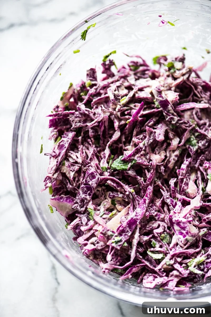 Effortless Mushroom Tacos 6 A large bowl filled with vibrant shredded red cabbage, fresh chopped cilantro, and light mayonnaise, ready to be tossed into a crunchy slaw for vegetarian tacos.