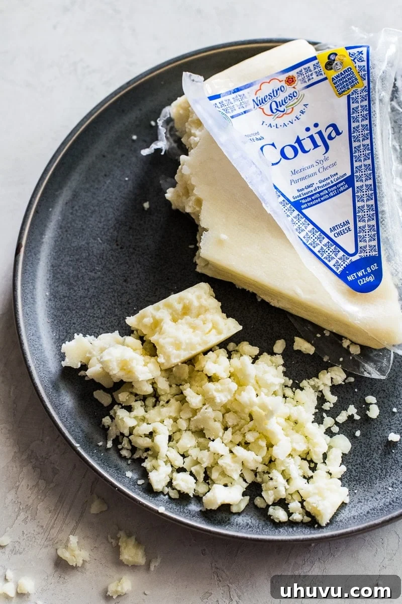 Cotija Cheese Unveiled Ingredients Substitutes and Culinary Uses 2 Crumbled cotija cheese on a gray stone plate, ready to be served or used as a topping.