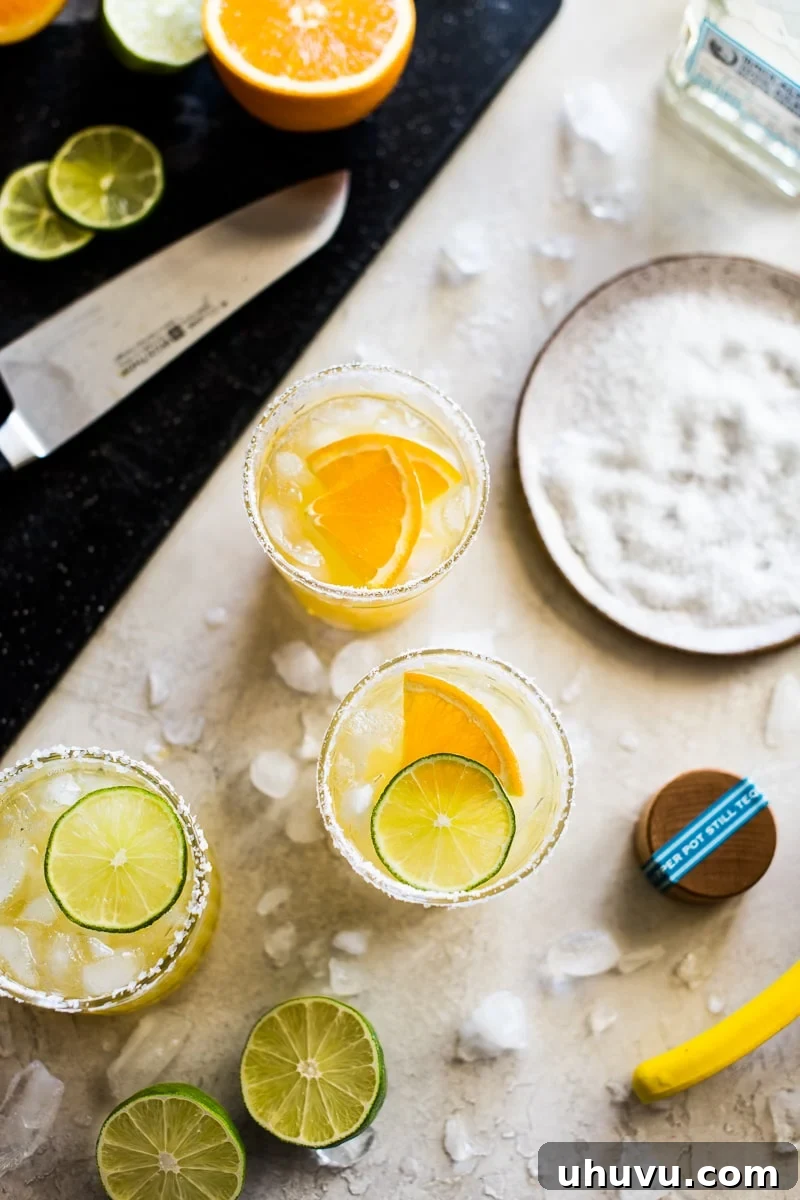 Skinny Margaritas ingredients laid out on a table: salt, limes, tequila, oranges, and ice cubes.