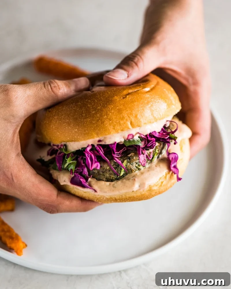 Hands holding a grilled turkey burger made with chipotle mayo and red cabbage slaw, showcasing its delicious layers.