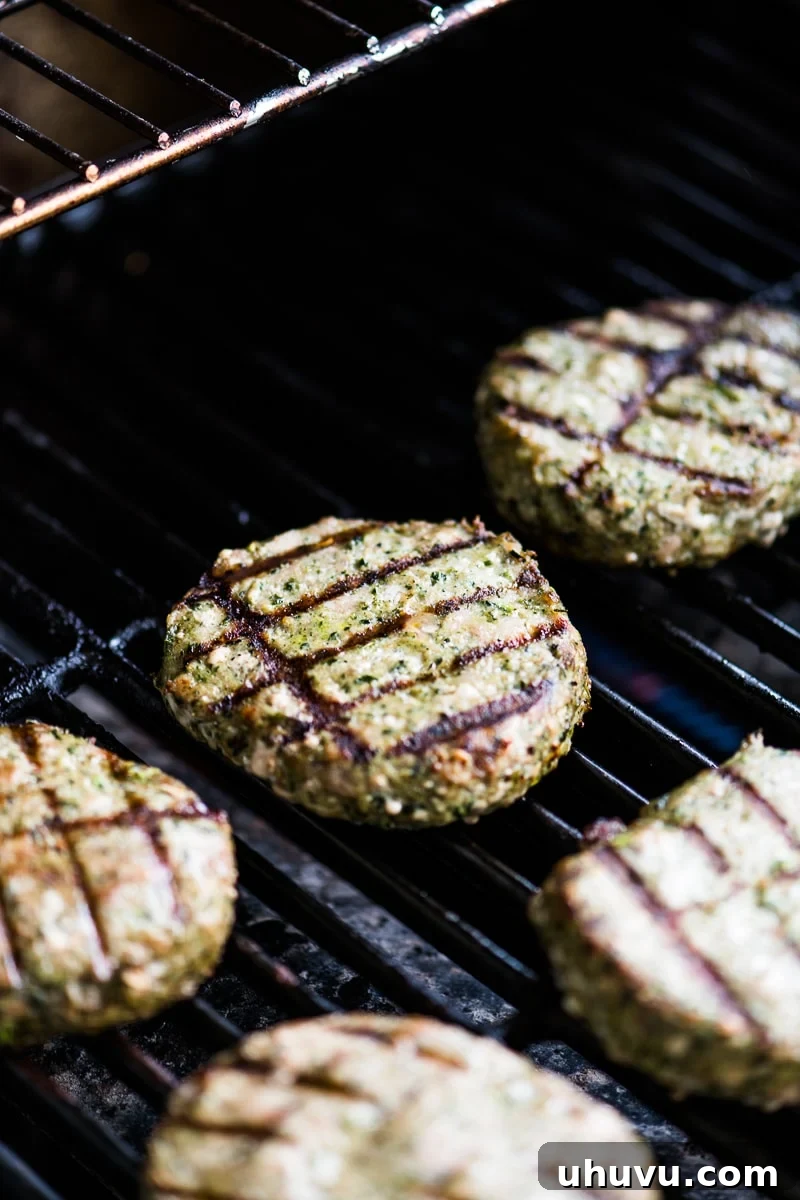 Honeysuckle White Spinach and kale turkey burgers sizzling on a hot grill, ready to be flipped and cooked to perfection.