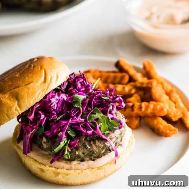 A grilled turkey burger sitting on a hamburger bun topped with chipotle lime mayo and a red cabbage slaw.