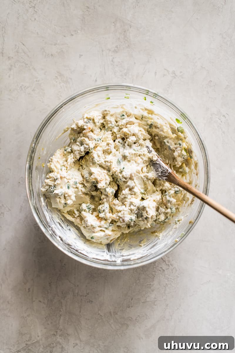 Jalapeno popper dip mixture in a glass bowl before being baked.