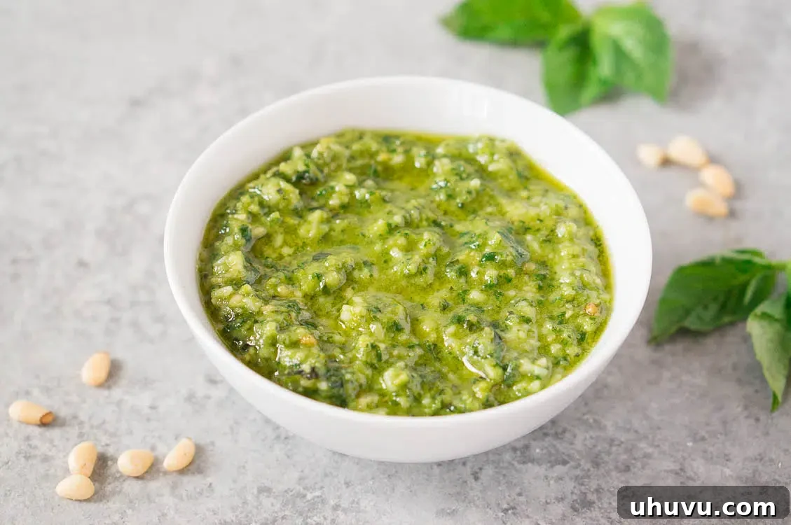 A bowl of fresh pesto sauce, garnished with basil leaves and pine nuts, ready to use