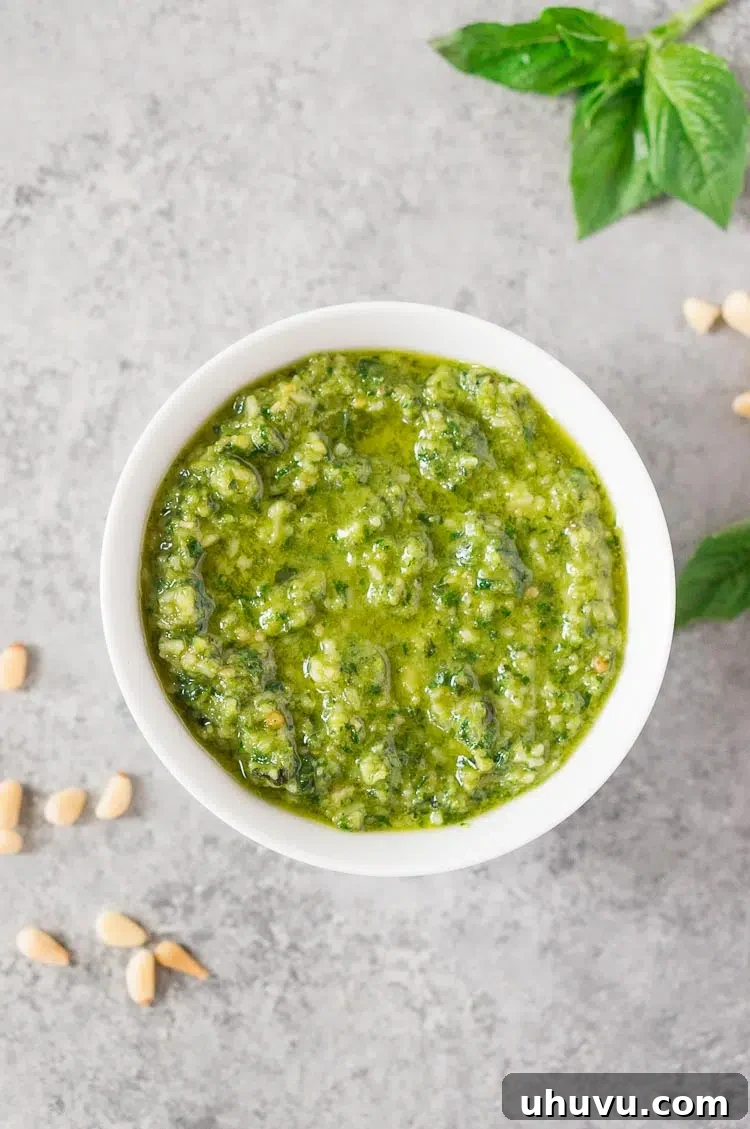 Close-up of vibrant basil pesto sauce in a pristine white bowl, showcasing its rich green color and texture