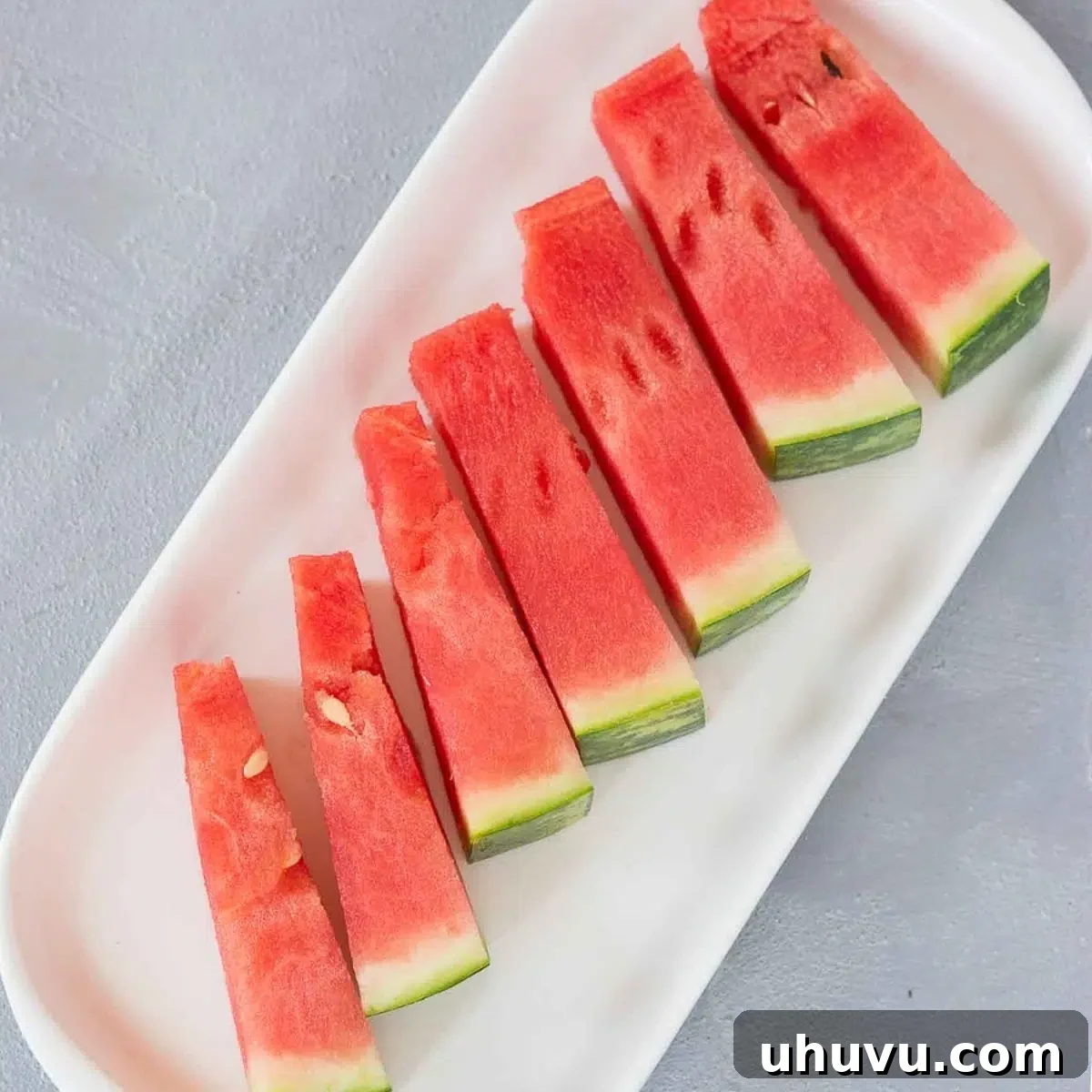 A plate of neatly arranged watermelon sticks, perfect for a casual snack.
