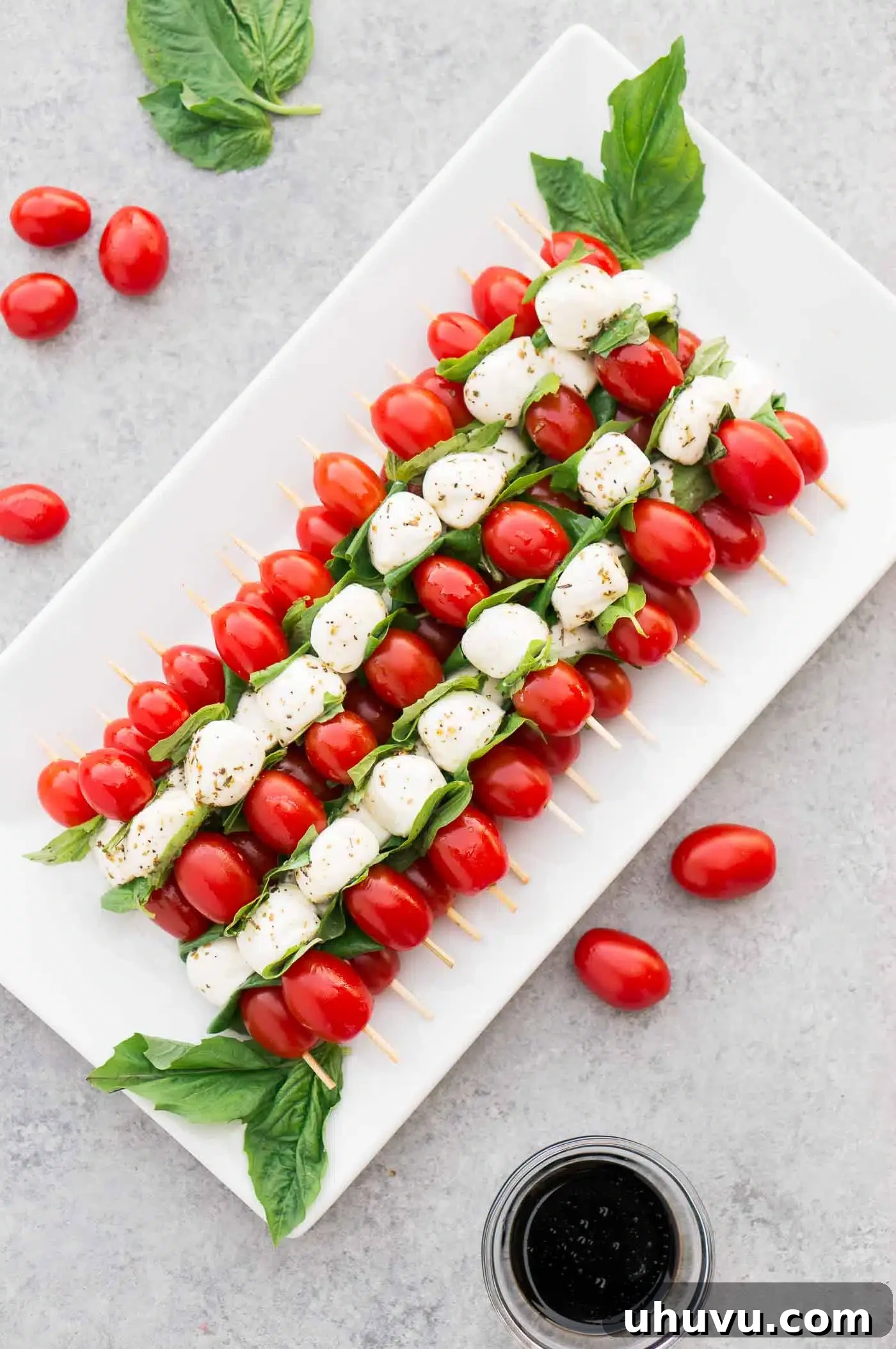 Fresh Caprese Bites 9 Vibrant Caprese tomato appetizer arranged artfully on a white platter with basil leaves, showcasing fresh ingredients