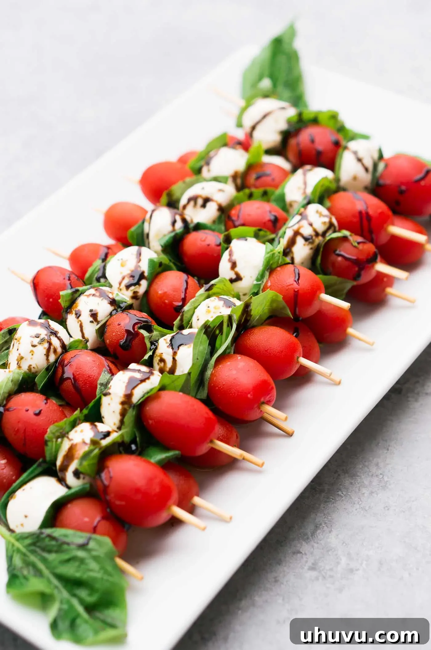 Platter of elegant mozzarella tomato skewers with basil and balsamic glaze, ready for serving at a party