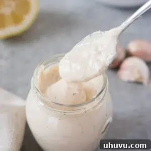 Scooping rich homemade Caesar dressing from a glass jar, ready to enhance any salad.
