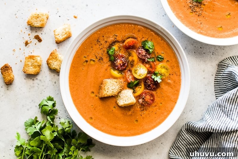Quick and Refreshing Gazpacho 6 A bowl of gazpacho garnished with vibrant halved cherry tomatoes, golden croutons, fresh cilantro leaves, and a glossy drizzle of olive oil.