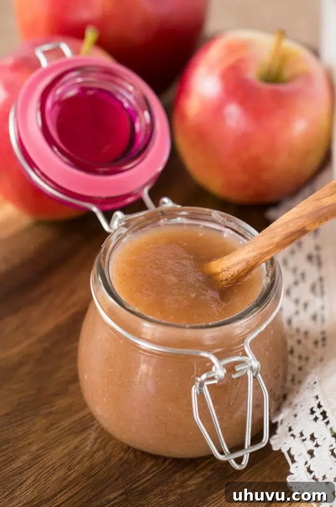 Homemade applesauce in the Instant Pot, with fresh apples in the foreground.