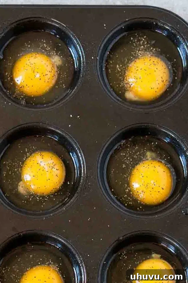 cracked eggs in a muffin tin ready for baking