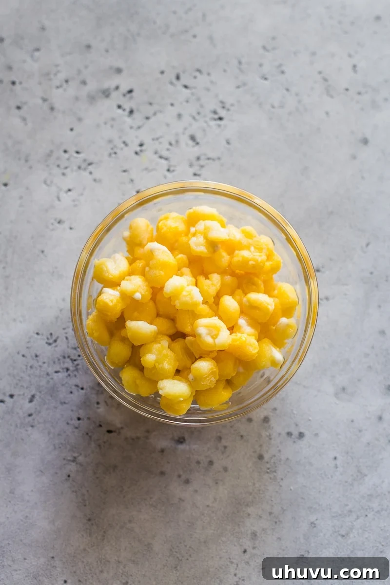 Golden yellow hominy in a small glass bowl, showcasing its rich color and plump texture.