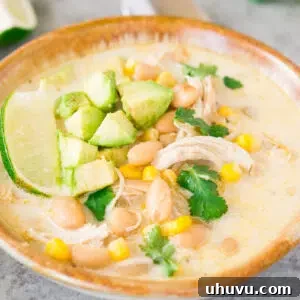 white chicken chili in a bowl topped with avocado cubes and lime slices