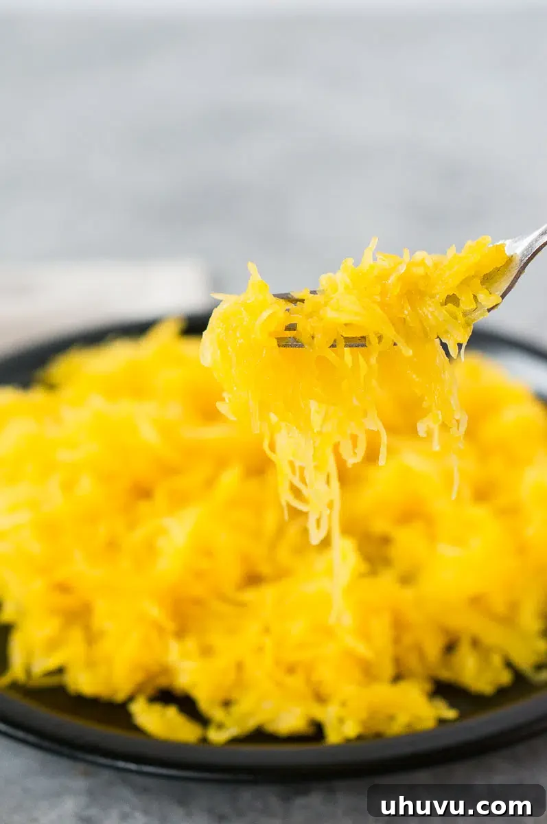 Close-up of a fork scooping cooked spaghetti squash strands from its shell.