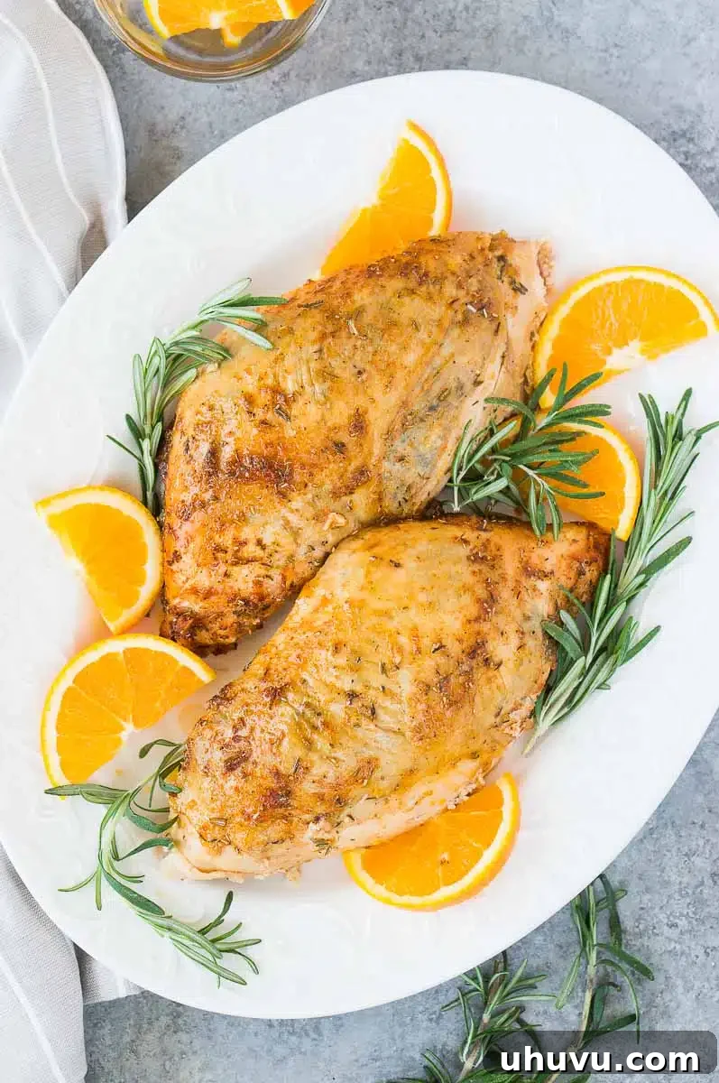 oven roasted turkey breasts on a platter with rosemary and orange slices