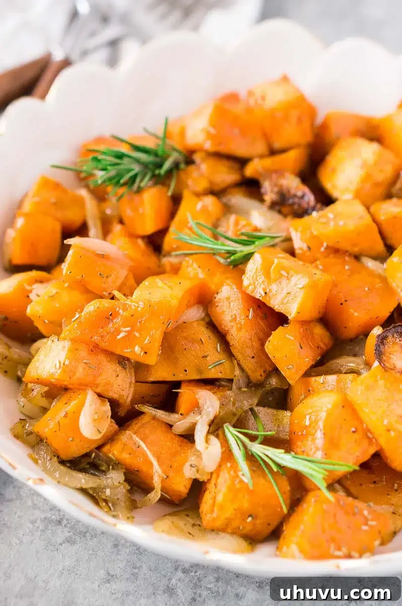 Close-up shot of perfectly roasted sweet potatoes and onions served in a white bowl, ready to be enjoyed