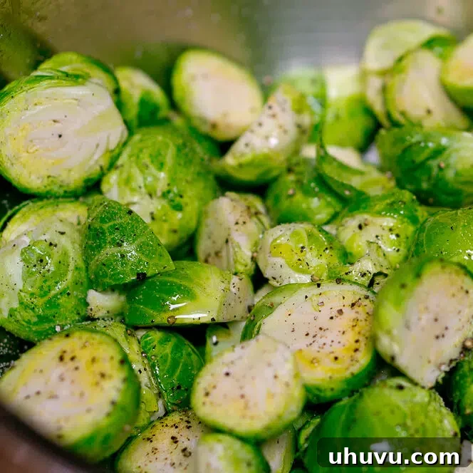 Washed and halved Brussels sprouts with garlic in a mixing bowl