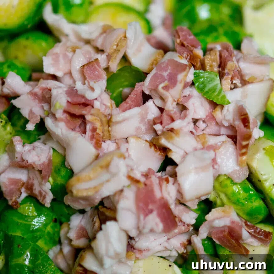 Brussels sprouts and diced bacon being tossed with olive oil, salt, and pepper in a bowl