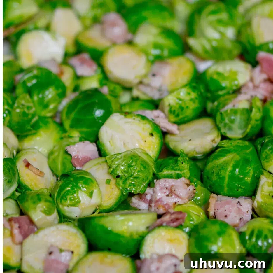 Seasoned Brussels sprouts and diced bacon spread in a single layer on a foil-lined baking sheet