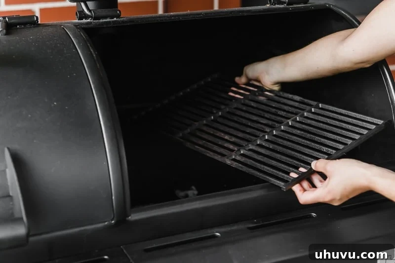 Hands carefully removing grill grates from a charcoal grill to prepare for lighting.