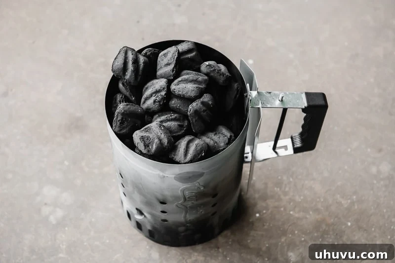 Charcoal briquettes neatly arranged and filling a metal chimney starter, ready for ignition.