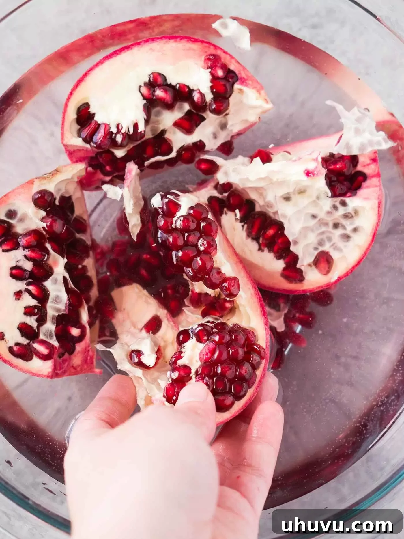 removing pomegranate arils in a bowl with water