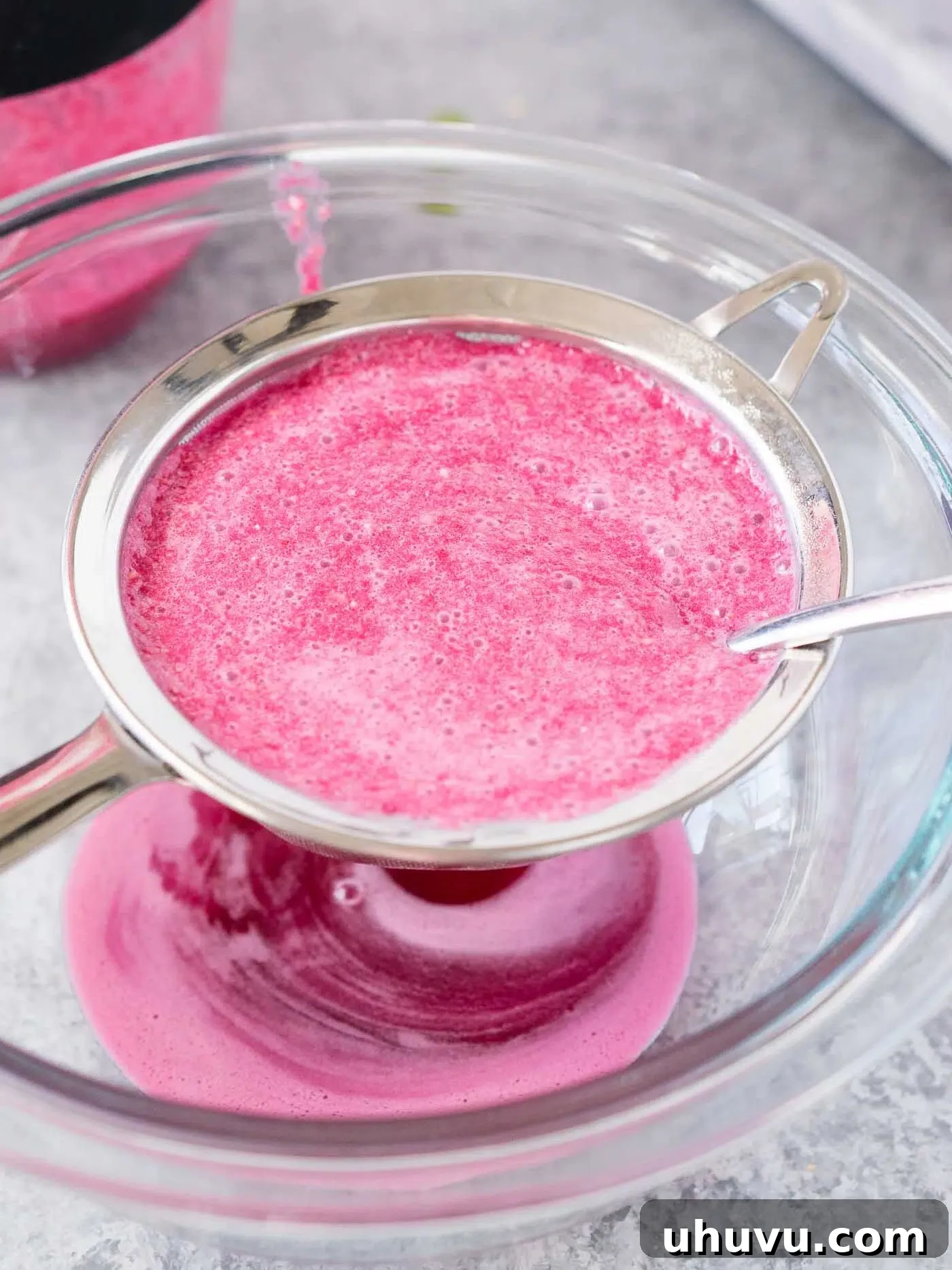 straining pomegranate juice through a strainer