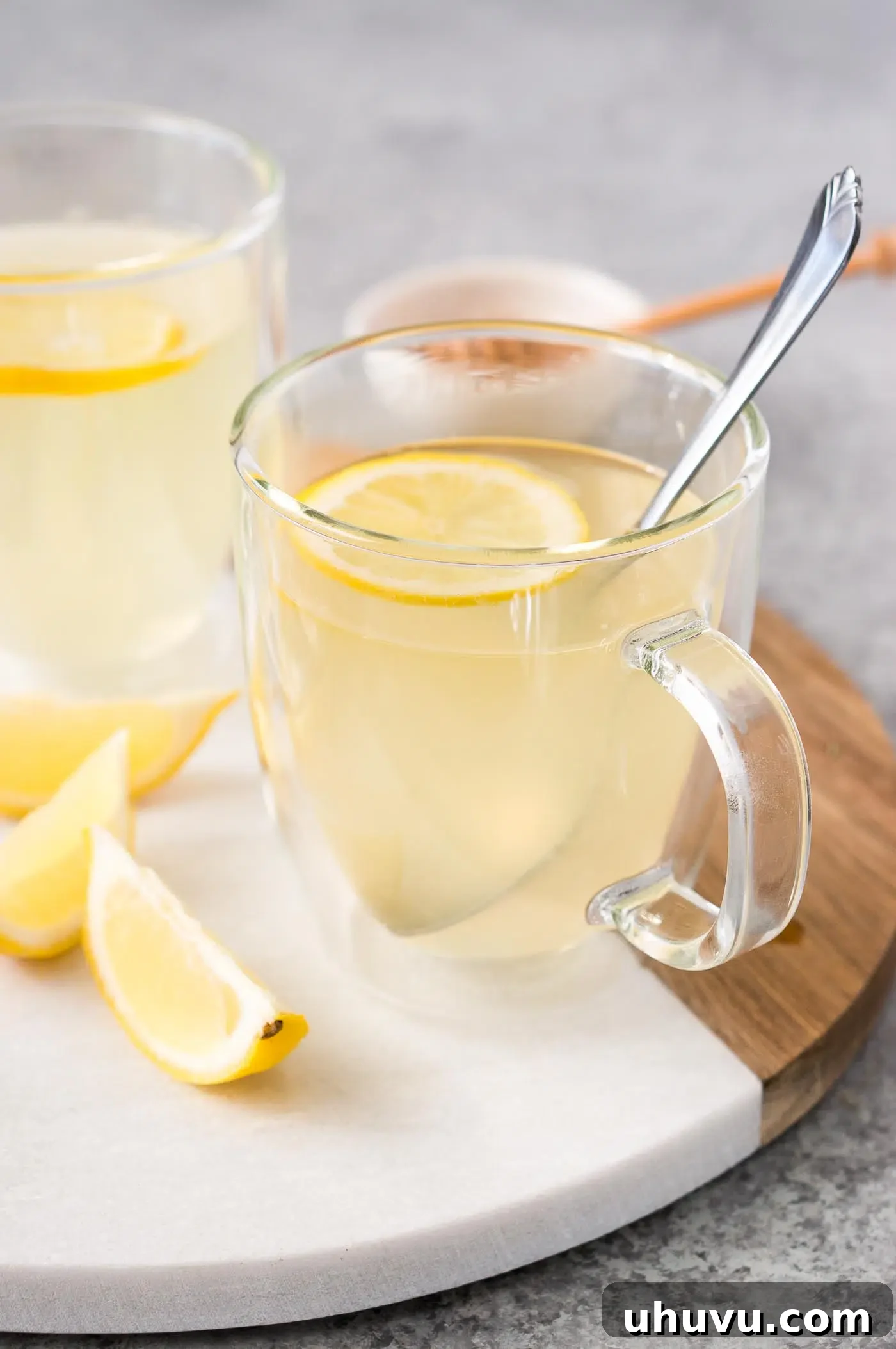 A beautifully presented glass cup of honey and lemon tea.